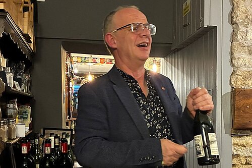 Daniel O'Keefe wielding a bottle of wine