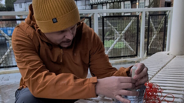 Cameron Thomas sits beside the River Avon at Tewkesbury helping to test water quality